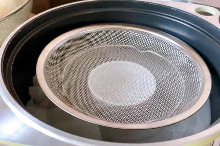 湯の中に耐熱皿を入れ、平ザルを乗せます