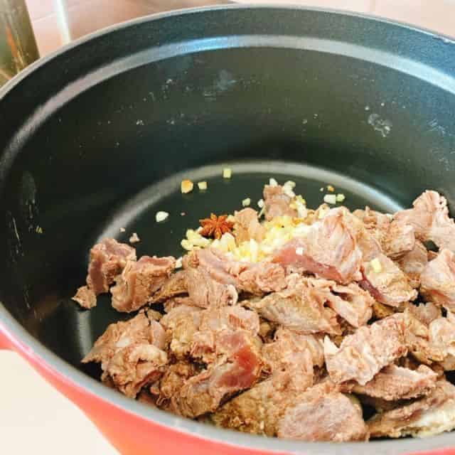 ホールスパイスとニンニク、玉ねぎ、牛すじを炒めます